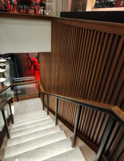 A stairway leading to a restaurant with wooden slats.
