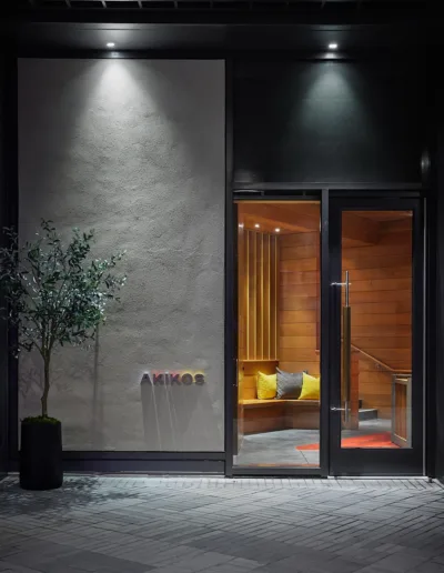 The entrance to a building at night with a potted plant.